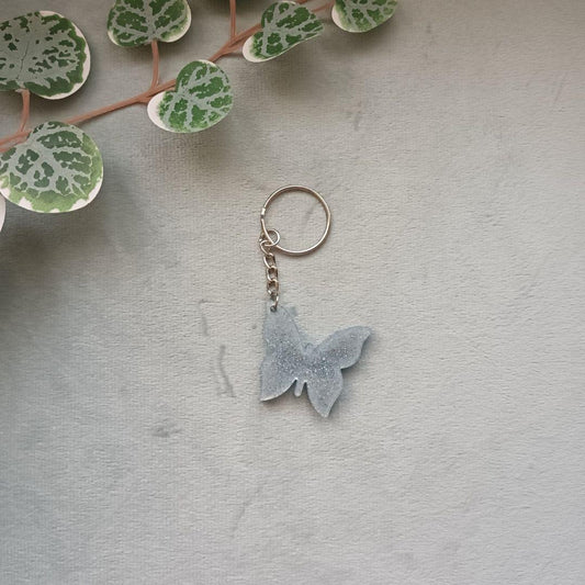 Porte-clé papillon en résine – Collection Ailes de Givre – Bleu transparent & pailleté argent – Cadeau féerique fait main