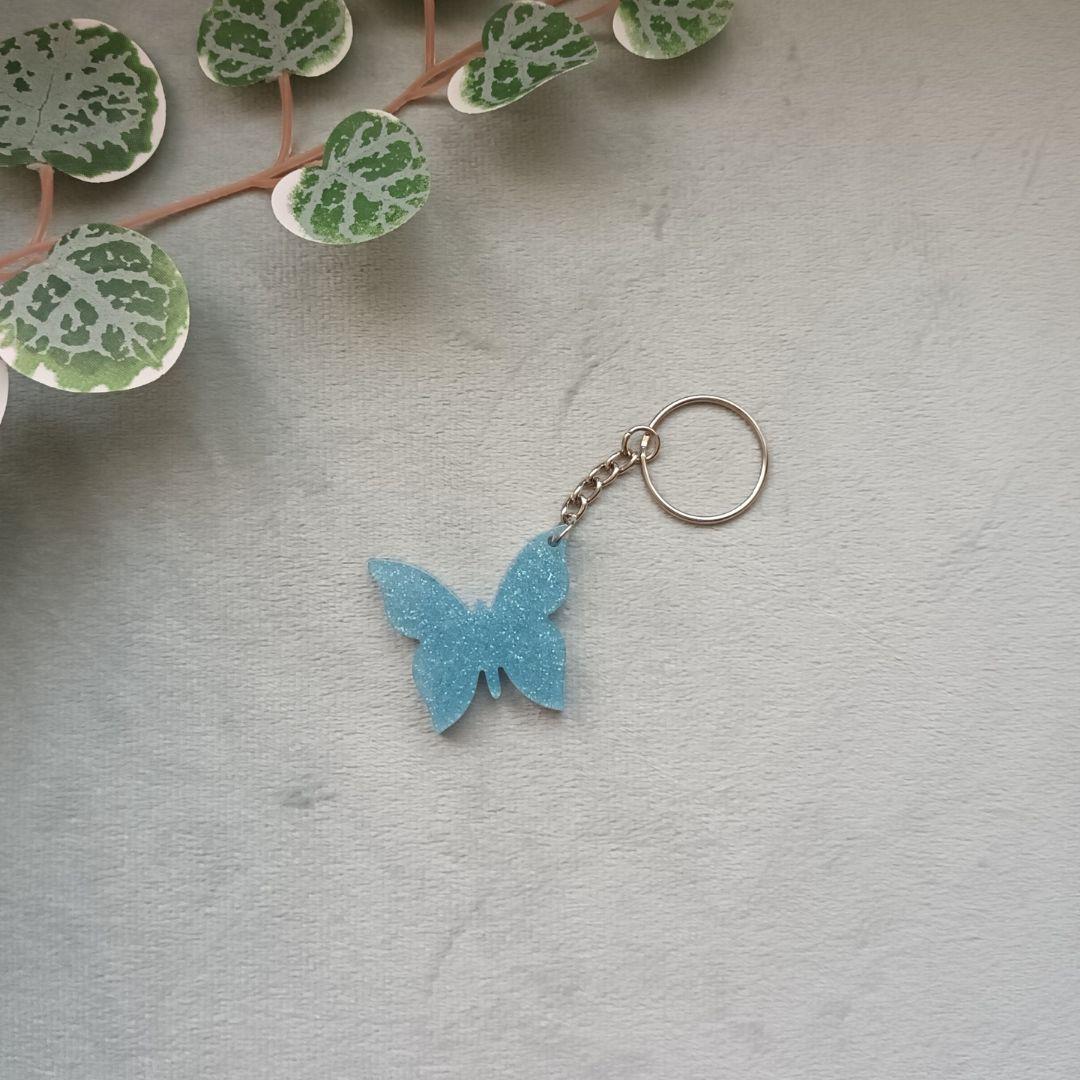 Porte-clé papillon en résine – Collection Ailes de Givre – Bleu transparent & pailleté argent – Cadeau féerique fait main